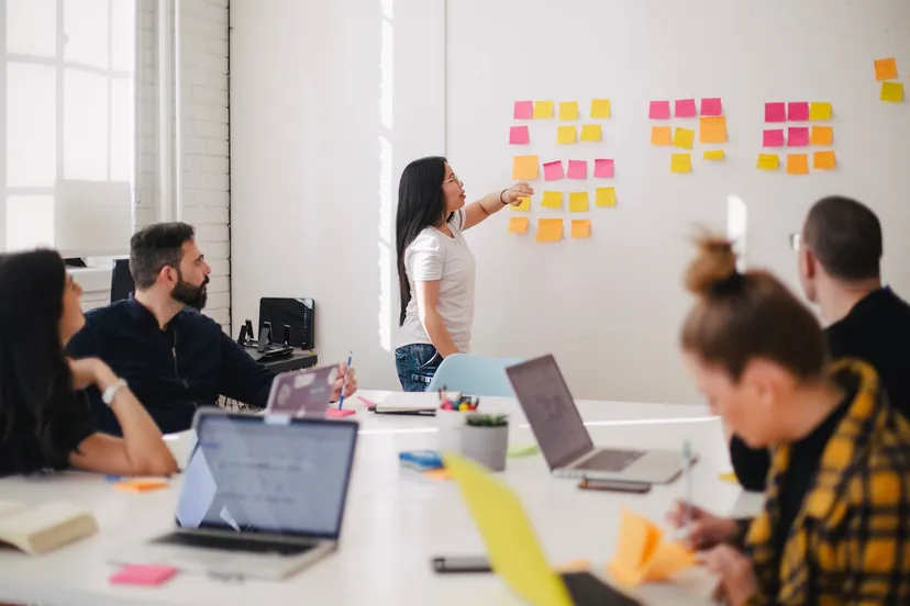 Team assembling ideas on a board of sticky notes